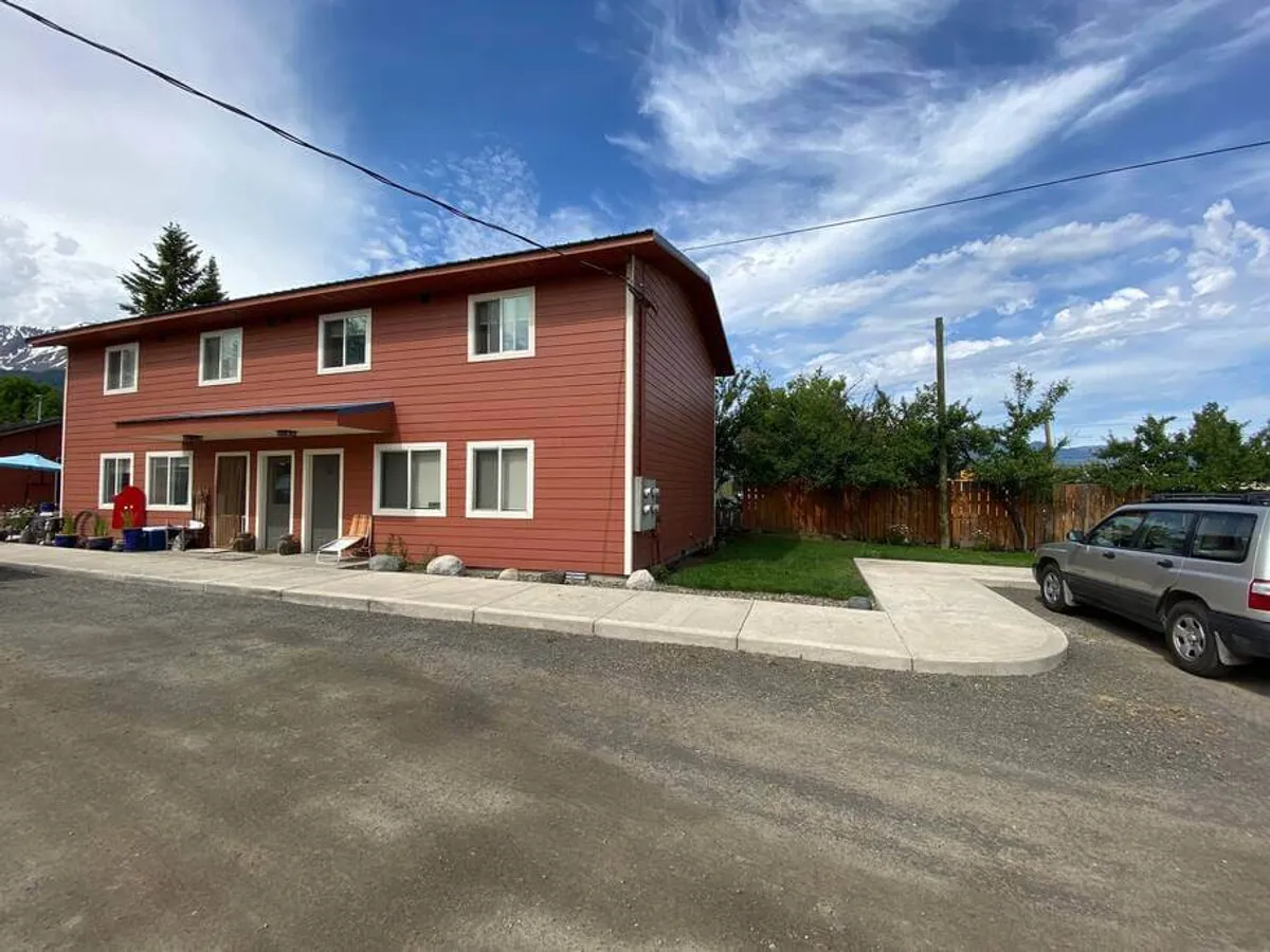 This image showcases the striking bright orange exterior of the building set against a vivid blue sky, with a well-manicured lawn and a visible driveway and parking area. The atmosphere is friendly and inviting, suggesting a welcoming community and easy access to local amenities.